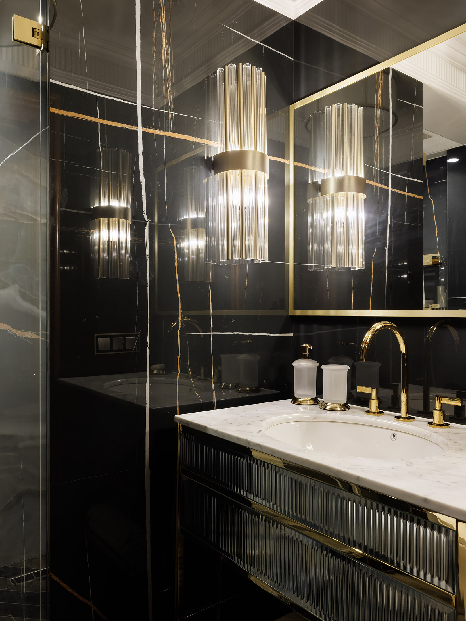 Раковина из мрамора Nero Marquina дополнена смесителями итальянского бренда NewForm. Унитаз с округлыми формами из коллаборации дизайнера Клаудио Сильвестрина и бренда Cielo.